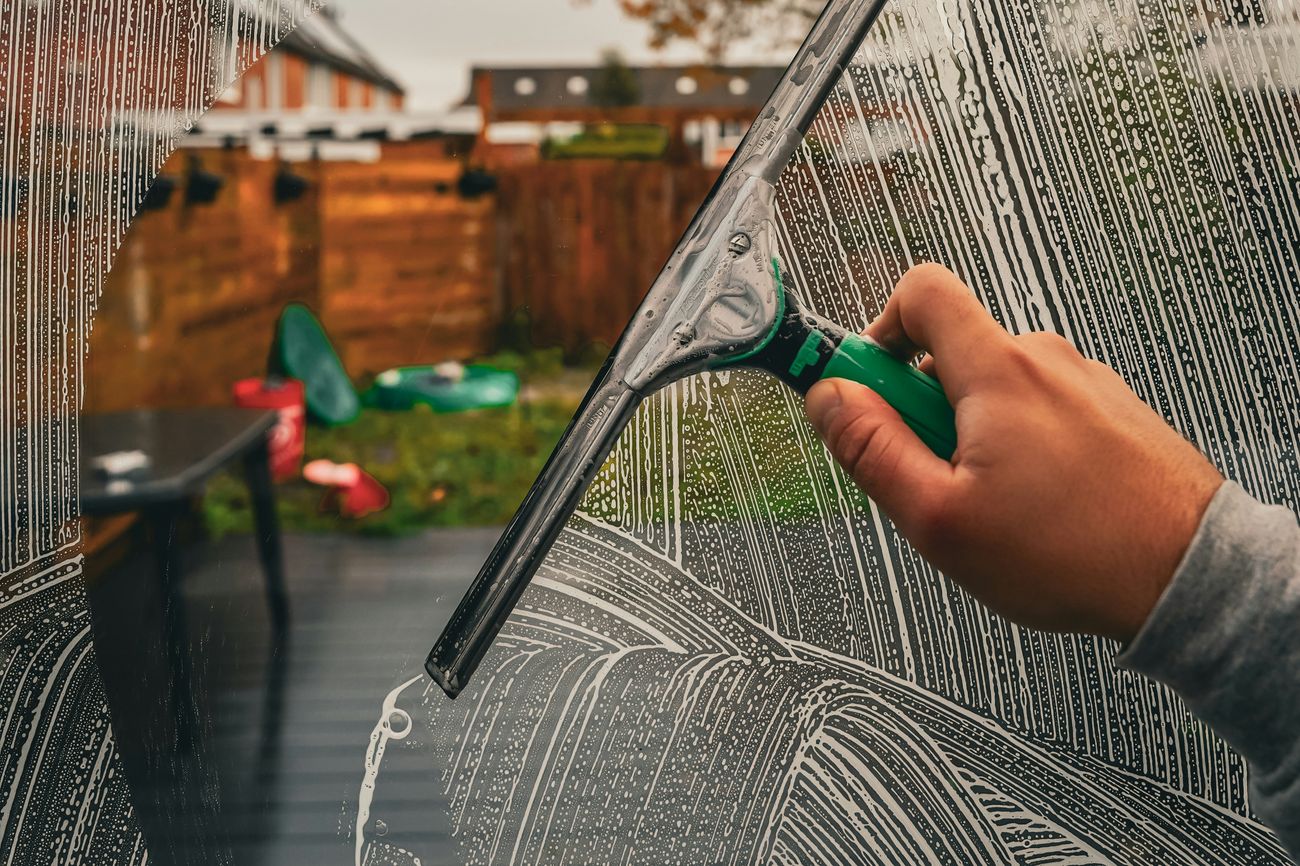 Squeegee cleaning a storefront window to a streak-free shine — Mega Function window cleaning service